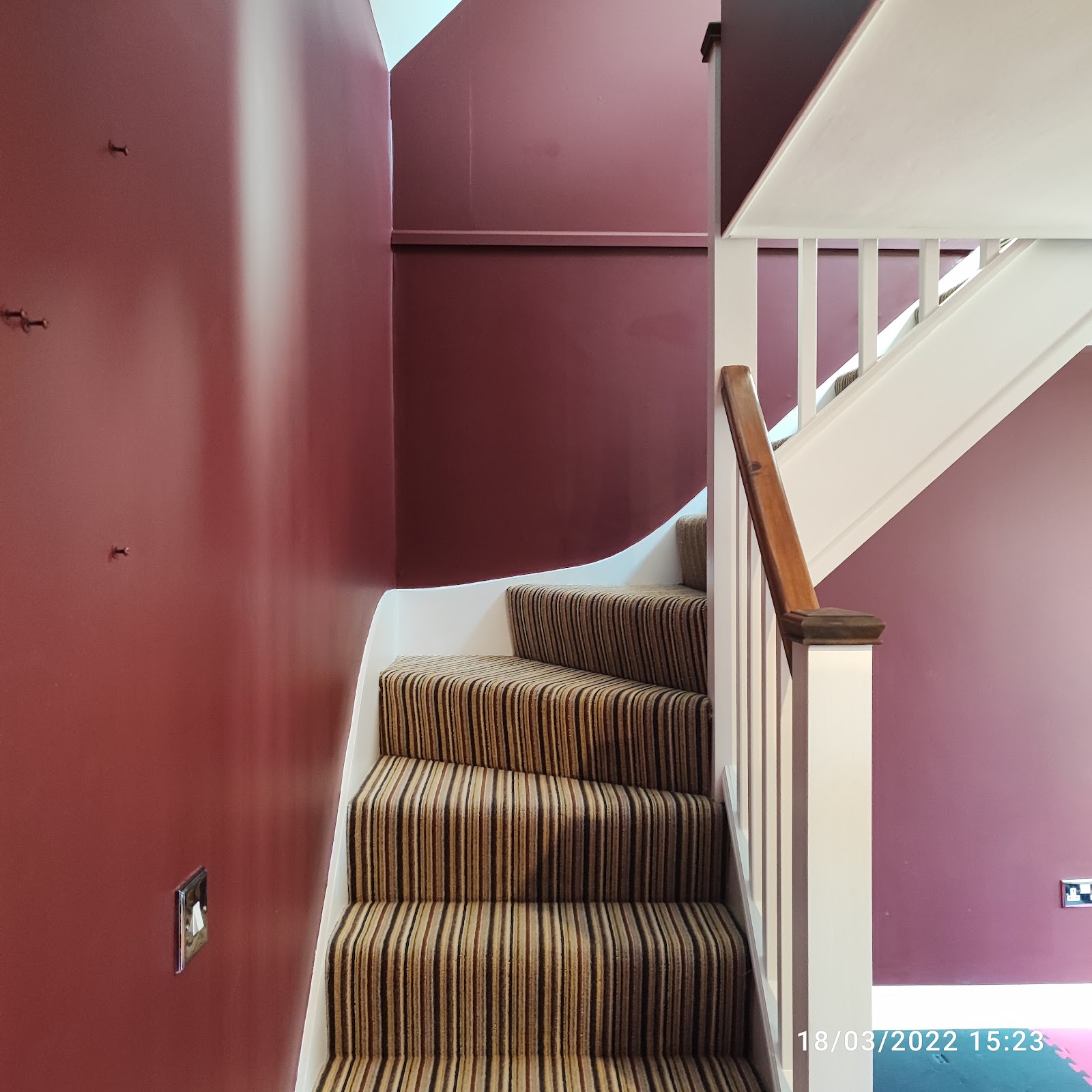A stairwell decorated in deep burgundy with a white banister
