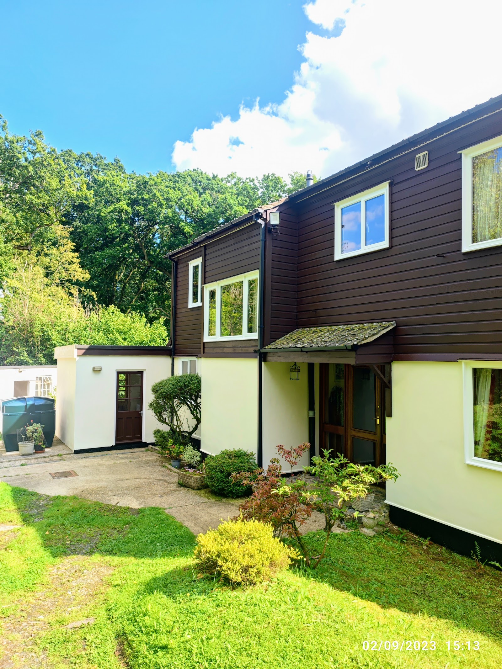 House exterior with dark brown timber cladding and cream render