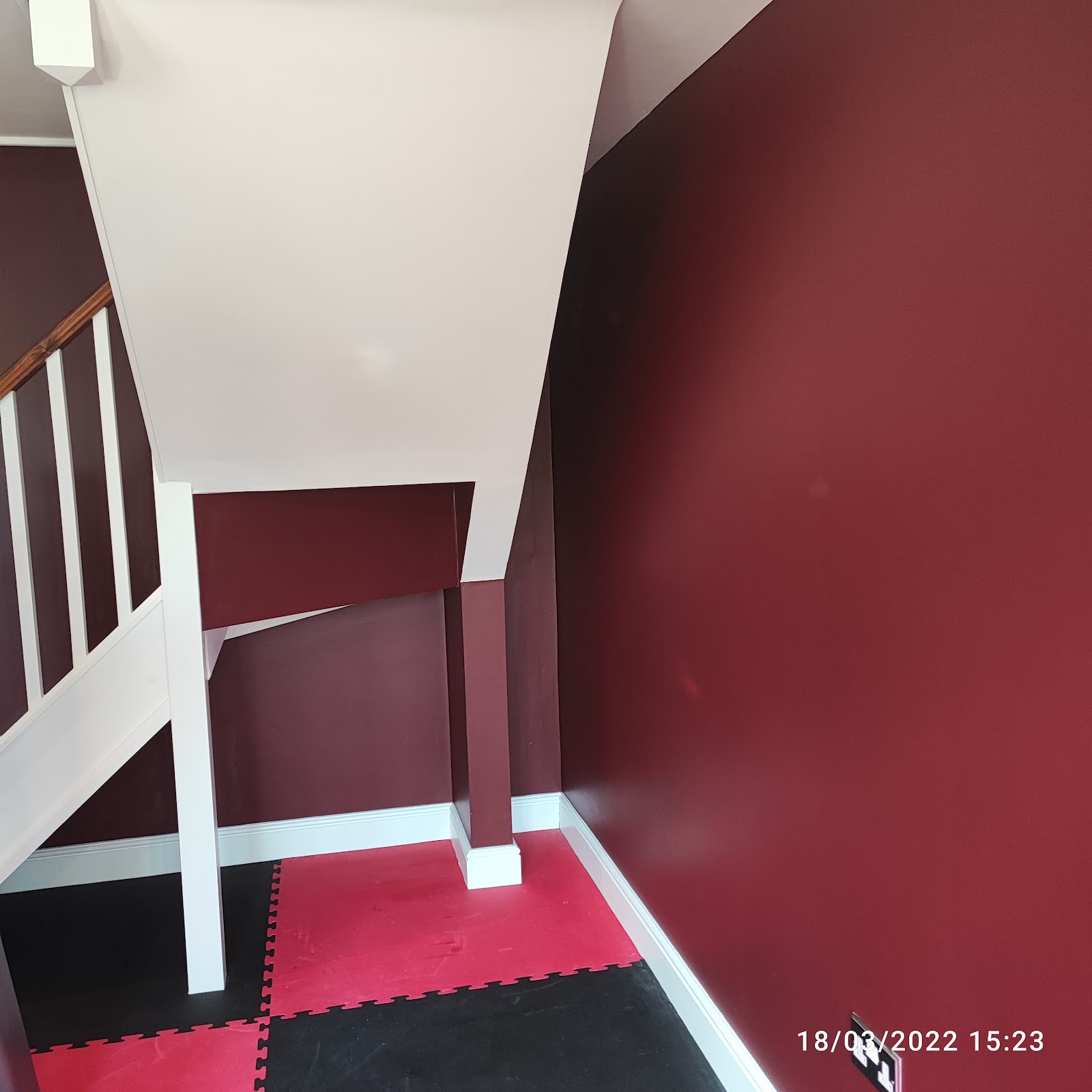 A burgundy hallway under the stairs with crisp white woodwork