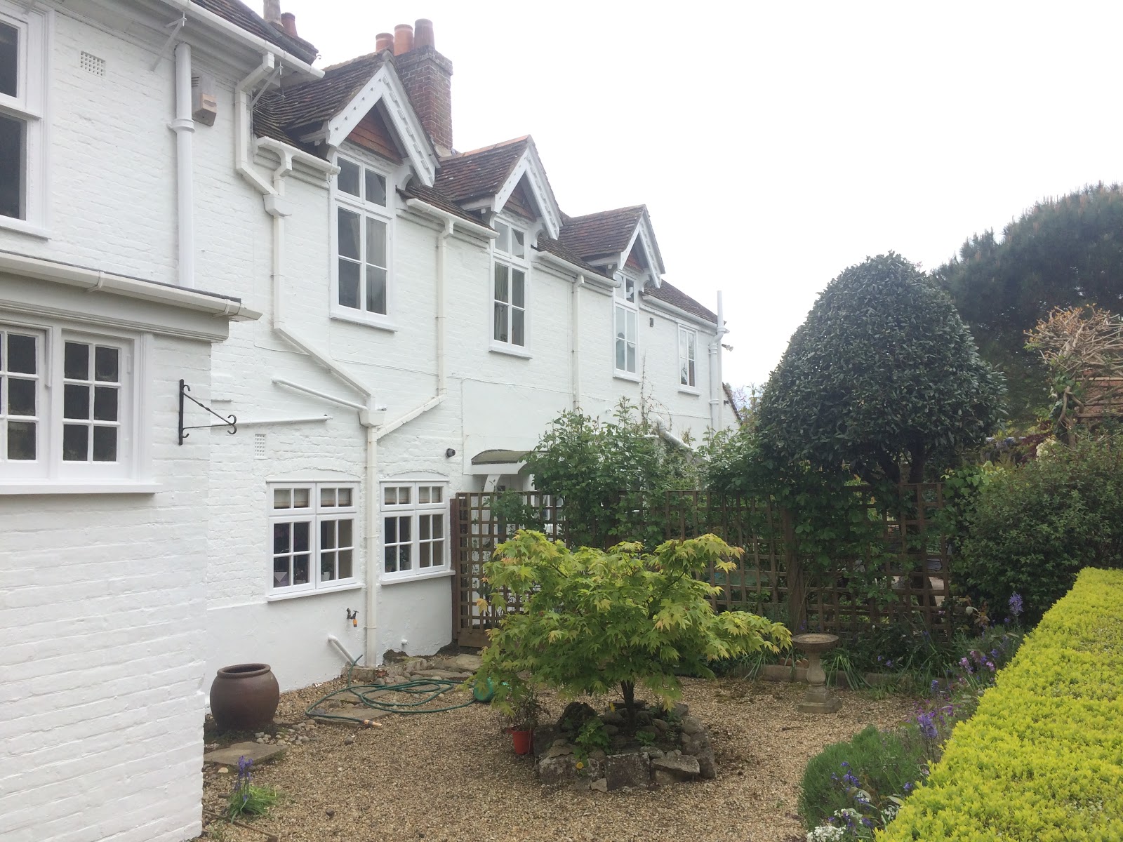 The white painted brick rear of a house above a gravel garden