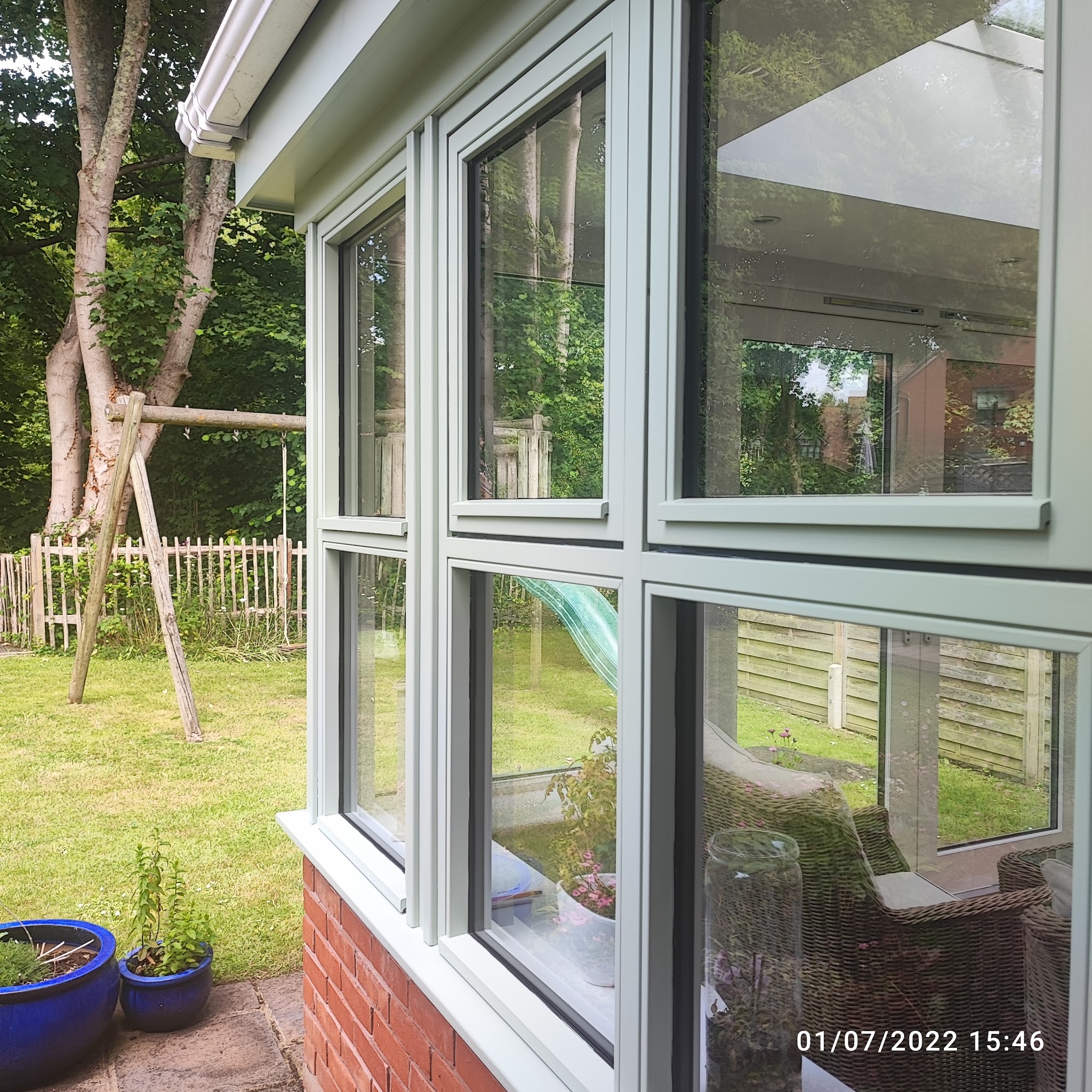 Sage green exterior timber windows looking onto a garden