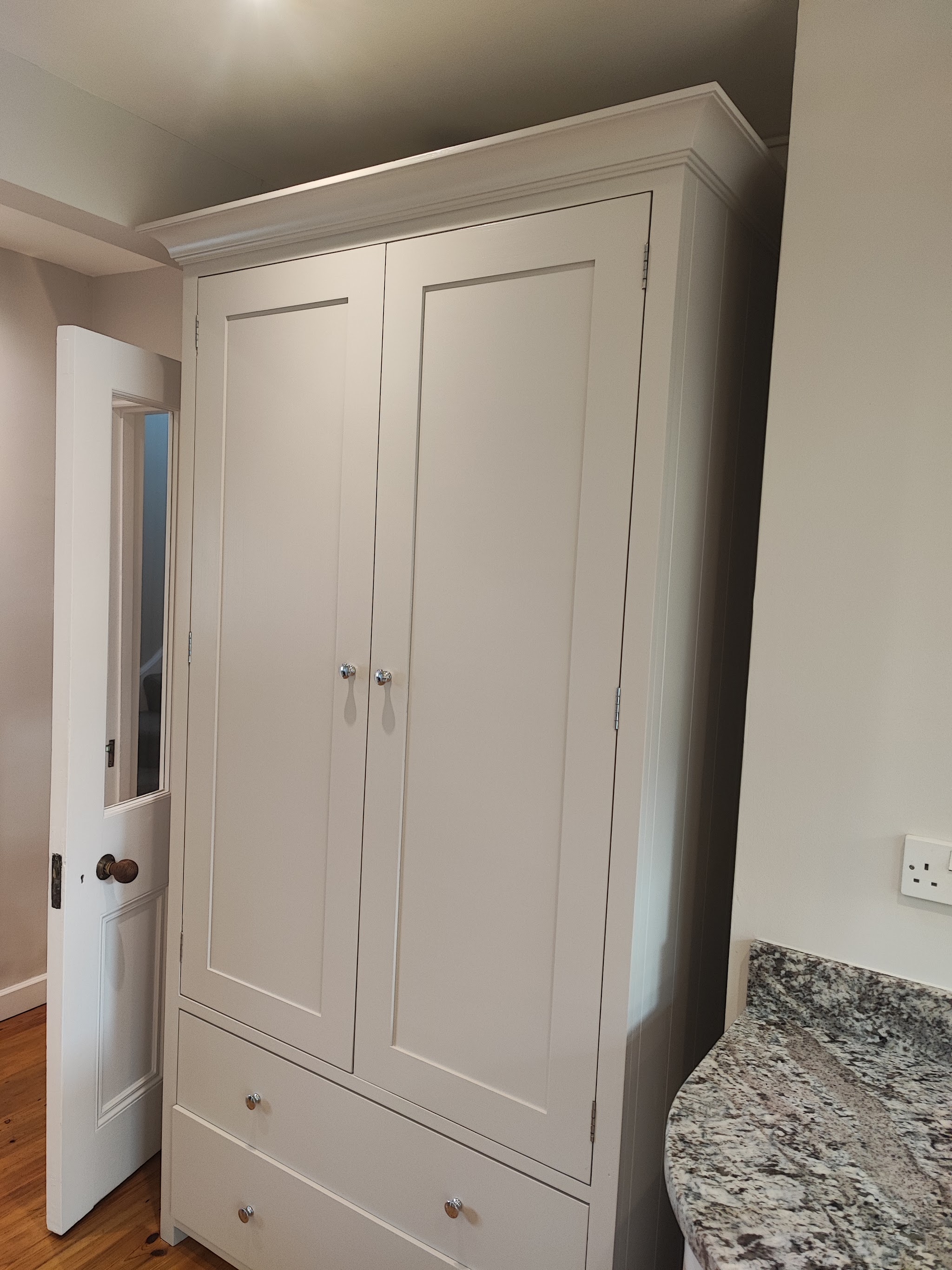 A tall double wardrobe hand-painted in pale grey