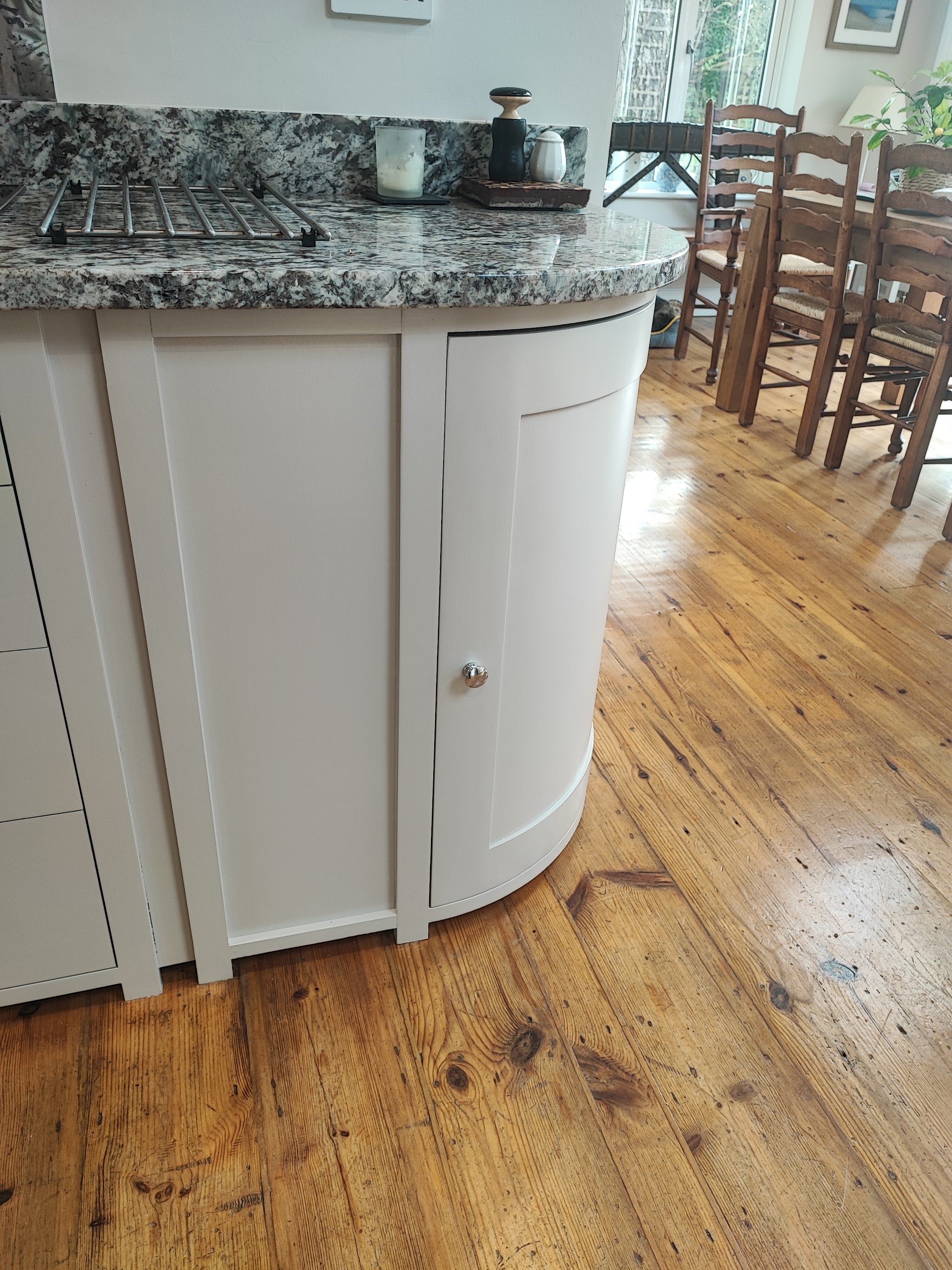 A curved painted kitchen island end on a pine floor