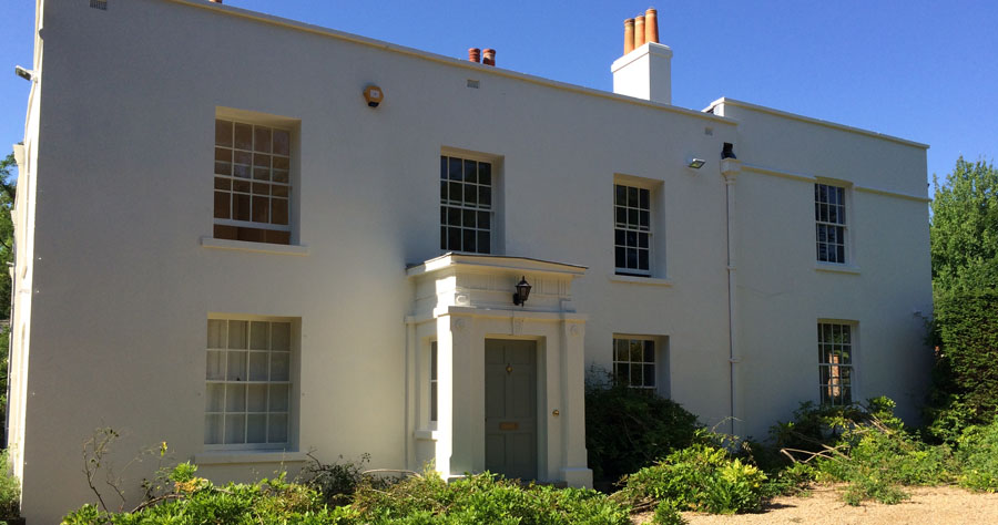 A white period house with a columned porch after restoration